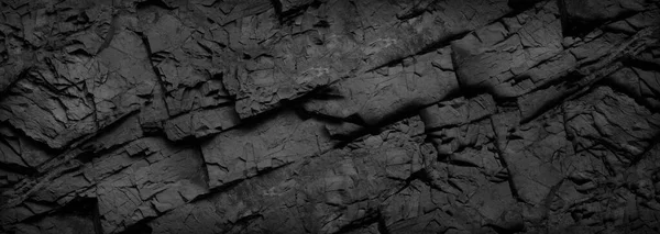 Black and white grunge. Rock texture. Dark stone background. Mountain surface texture. Close-up. It looks like an old brick wall. Baner with black grunge background. Copy space.