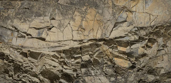 Rock texture. Stone background. Old weathered crumbling mountain surface in cracks background. Light brown rock background.