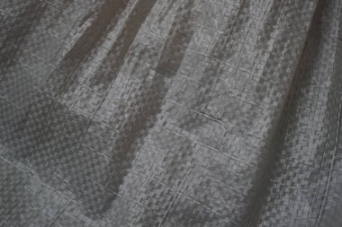 Buruşuk kumaş dokusu. Polipropilen. Yapay kumaşın kabataslak yüzeyinin dokusu. Beyaz gri grunge doku arkaplanı.