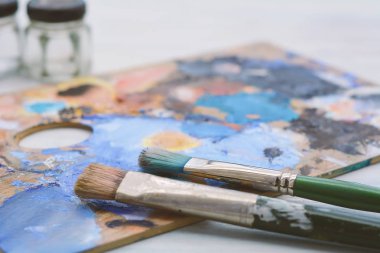 Sanatçının renkli yağlı boya konturları, kavanoz ve Beyaz ahşap zemin üzerinde Boya fırçaları paletle. Sanat kavramı