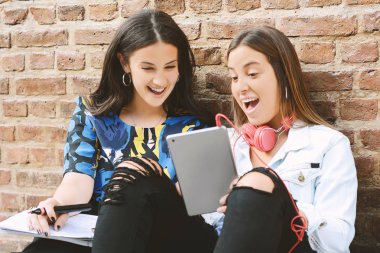 İki kız öğrenci çalışma kitabı ve tablet Pc kentsel arka planda sınavlarına hazırlanıyor. Eğitim kavramı.