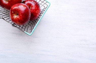 Olgun Kırmızı elma Beyaz ahşap zemin üzerinde alışveriş sepeti dolu.