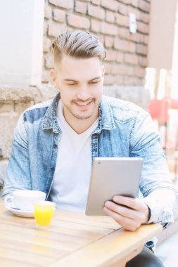 Tablet kullanarak mutlu genç adam portresi. Açık havada