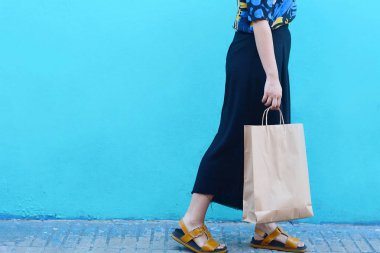 Renkli bir kentsel duvara alışveriş torbaları ile yürüyen genç kadın görünümünü kapatın. Alışveriş concep