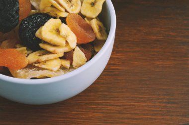 Ahşap arka plan üzerinde farklı kurutulmuş meyve bir kase kapatın. Sağlıklı gıda