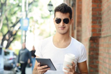 Kahve tutarak ve tablet kullanma genç latin adam. Uraban sahnesi