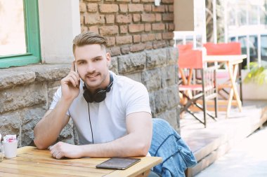Genç adam telefonda konuşurken kafede. Açık havada