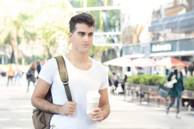 Kahve güneşli parkta tutan genç çekici bir adam. Concep götür