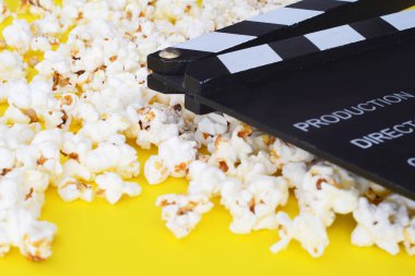 Lezzetli popcor ve sarı zemin üzerine fıçı tahtası. Sinema kavramı