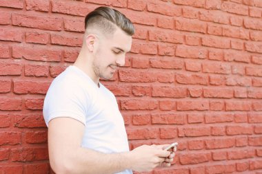 Telefonunda daktilo eden genç Latin adamın portresi. Açık havada..