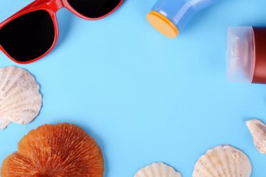 Üstten Görünüm güneş gözlüğü, kabukları, deniz yıldızı ve güneş kremi ile boşaltmak. Yaz konsepti. Açık mavi renkli 