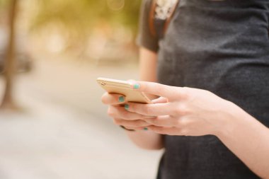 Onun smartphone ile bahseden bir genç güzel kadın portresi. Açık havada.