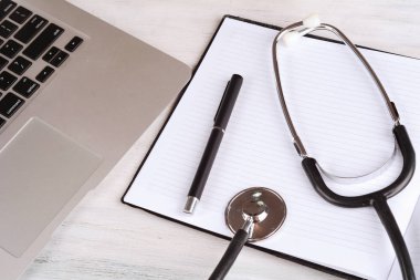 Üstten Görünüm dizüstü bilgisayar, not defteri ve doktor masada tethoscope. Modern tıp işyeri 