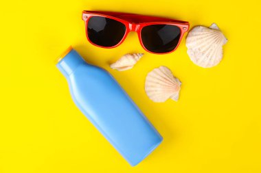 Üstten Görünüm güneş gözlüğü, kabukları, deniz yıldızı ve güneş kremi ile boşaltmak. Yaz konsepti. Açık mavi renkli 