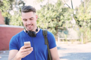 Telefonunda daktilo eden genç Latin adamın portresi. Açık havada..