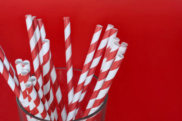 Colorful paper straws with copyspace on red background