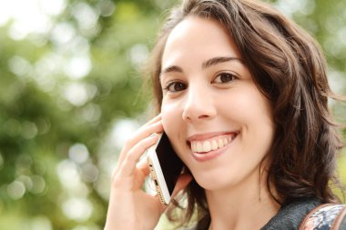 Genç latin kadın cep telefonu üzerinde söz portresi. Açık havada.