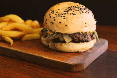 Taze lezzetli hamburger ve patates kızartması ahşap kesme tahtası üzerinde kapatın. Sağlıksız yiyecek konsepti.