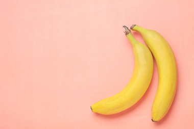 Üstten görünüm. Pembe bir arka plan üzerinde muz. Sağlıklı kavramı