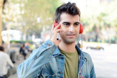 Kulaklık ile müzik dinlemek genç latin adam portresi. Açık havada.