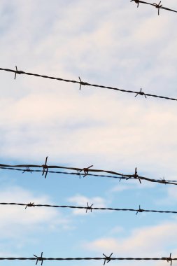 Mavi Gökyüzü bulutlu karşı dikenli tel çit.