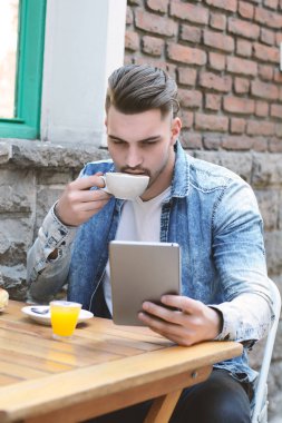 Genç adam bir tablet kullanarak kafe Cafe. Açık havada