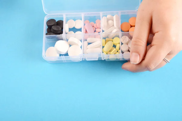 Close up of hand showing medicine box with pills on Blue backgroun