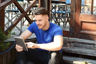 Tablet kullanarak mutlu genç adam portresi. Açık havada