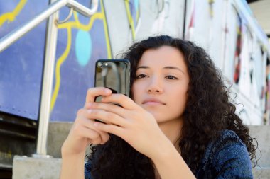 güzel genç latin kadınlar sokakta smartphone ileti gönderme.