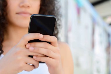 Sokakta akıllı telefonunu kullanan genç Latin kadın.