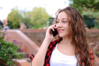 Genç kadın cep telefonu üzerinde söz portresi. Açık havada.