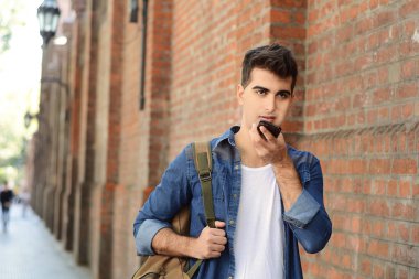 Sesli mesaj gönderme genç latin adam portresi. Açık havada. Kentsel sahne.
