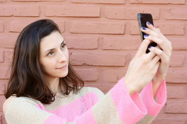 Selfie onun smartphone ile alarak güzel genç bir kadın portresi. Açık havada.