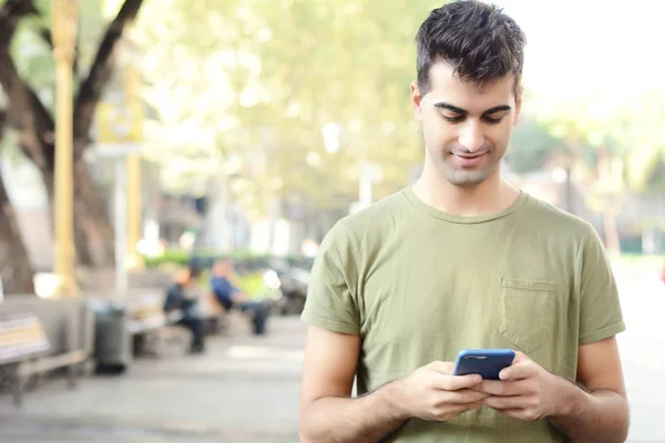 Egy Fiatal Latin Férfi Portréja Amint Gépel Telefonján Szabadtéri — Stock Fotó