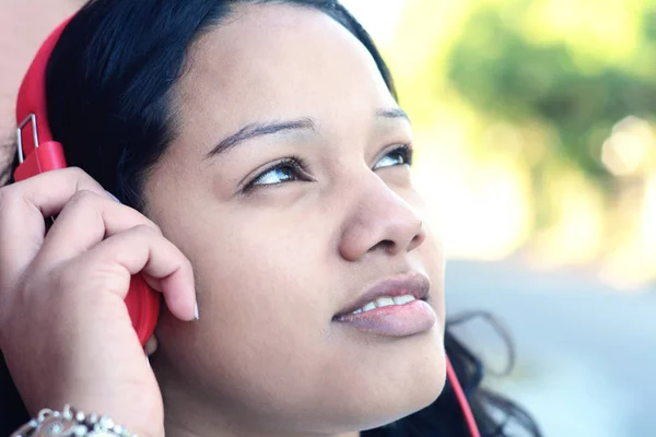 年轻的拉丁妇女的肖像与耳机听音乐 欣赏音乐 — 图库照片