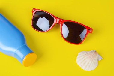 Üstten görünüm güneş gözlüğü, kabukları, deniz yıldızı ve güneş kremi. Yaz konsepti.