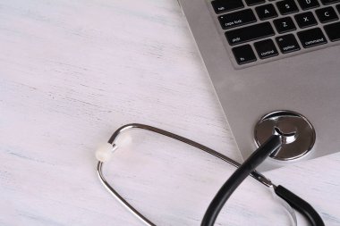 Üstten Görünüm dizüstü bilgisayar, not defteri ve doktor masada tethoscope. Modern tıp işyeri 