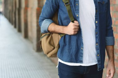 Genç adam bir sırt çantası ile sokakta yürürken görünümünü kapatın. Açık havada