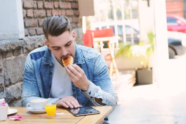 Genç adam bir tablet kullanarak kafe Cafe. Açık havada