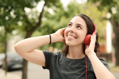 Kırmızı kulaklıklarla müzik dinleme genç güzel kadın portresi. Açık havada. Kentsel kavramı.