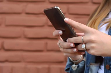 Onun smartphone sahip iletileri gönderme güzel genç bir kadın portresi. Açık havada.