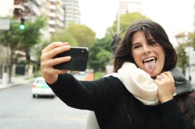 Selfie onun smartphone ile alarak güzel genç bir kadın portresi. Açık havada.