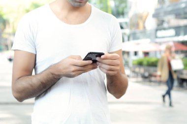 Telefonunda daktilo eden genç Latin adamın portresi. Açık havada..