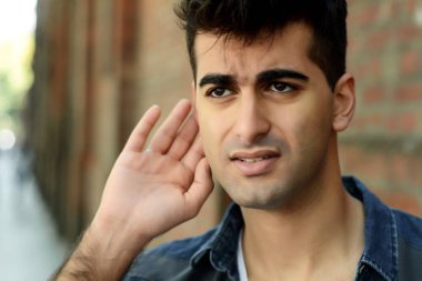 etkileyici delikanlı kulağını ve bir şey dinlerken elini tutar. Açık havada.