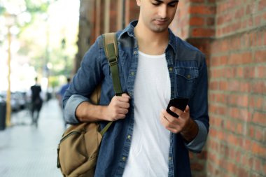 Telefonunda daktilo eden genç Latin adamın portresi. Açık havada..