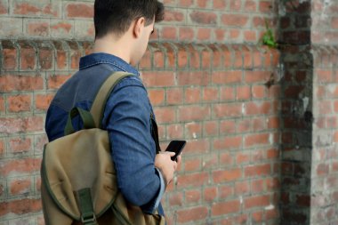 Telefonunda daktilo eden genç Latin adamın portresi. Açık havada..