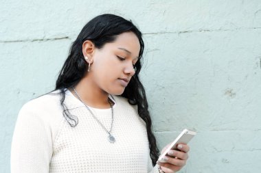 Sokakta akıllı telefonunu kullanan genç Latin kadın.