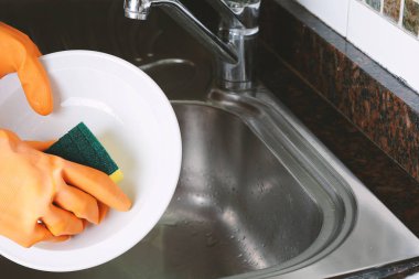 Sünger ile bulaşık eldivenleri elinde yakından görmek. Ev kavramı