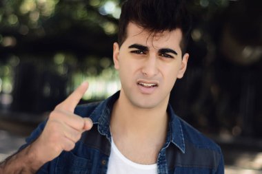 Genç latin adam kameraya bağırarak portresi. Açık havada