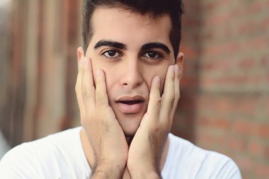 Genç latin adam merak yüz ifadesinde portresi. Açık havada